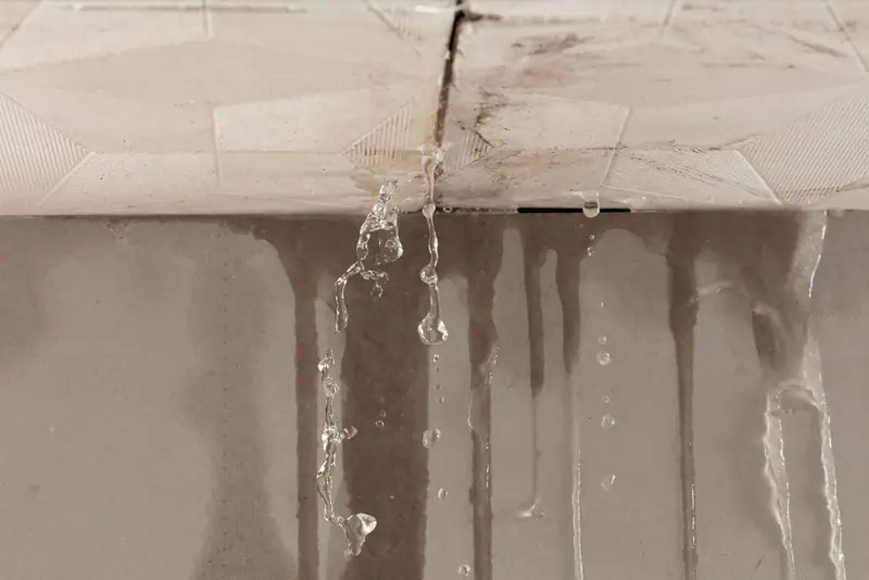 Rainwater dripping through a stained ceiling from a leaking roof