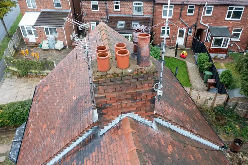 Brick chimney stack with terracotta pots and lead flashing, seen from above on a tiled roof